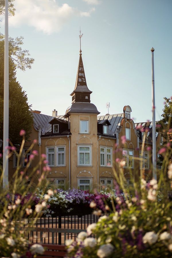 Hus i bakgrunden i fokus, blomsterplanteringar i förgrunden.